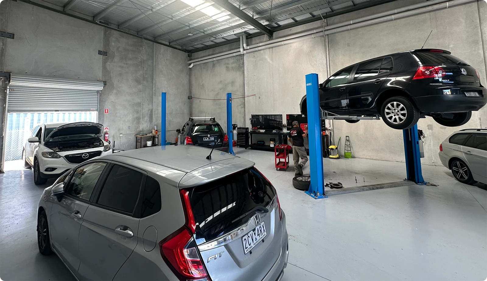 Car raised on a blue two post hoist in the Moolap workshop