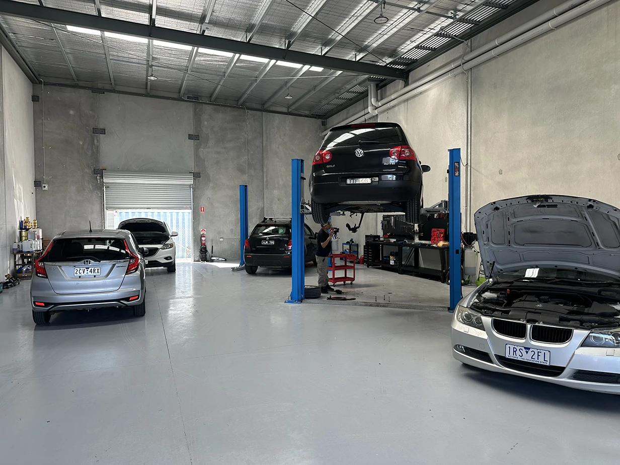 Inside the 13 Automotive workshop with cars on hoists and the roller door open