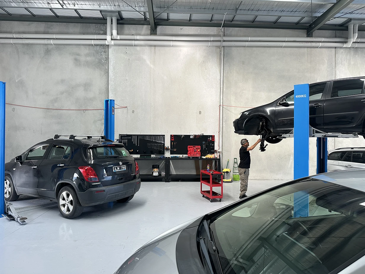 Mechanic working under a car raised on a hoist at the 13 Automotive workshop in Moolap