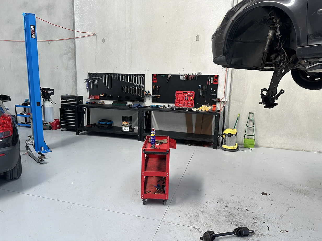 Car raised on a hoist with a wheel off for inspection